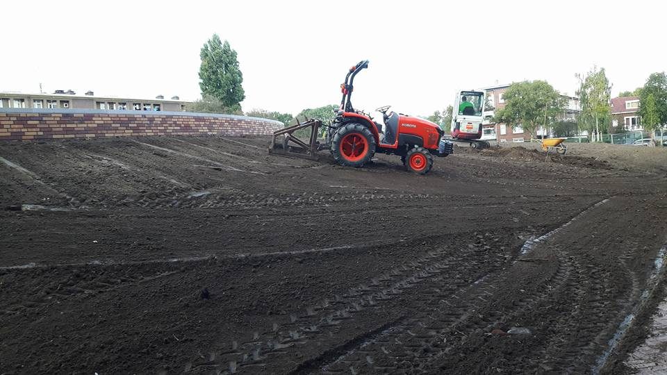 Een trekker egaliseert de grond van een terrein voordat er gras wordt ingezaaid