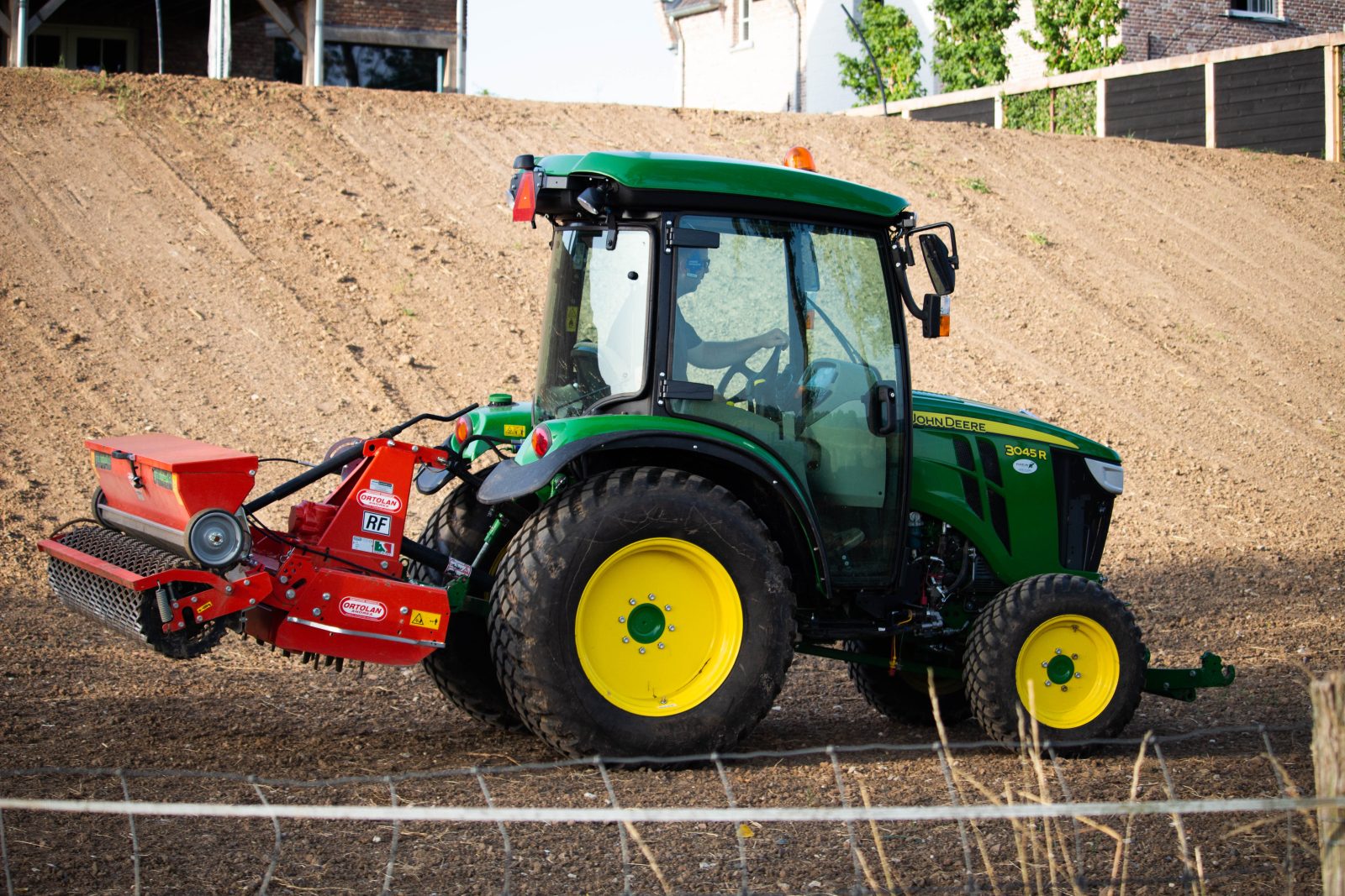 Een trekker met zaaimachine zaait gras in op bewerkte grond