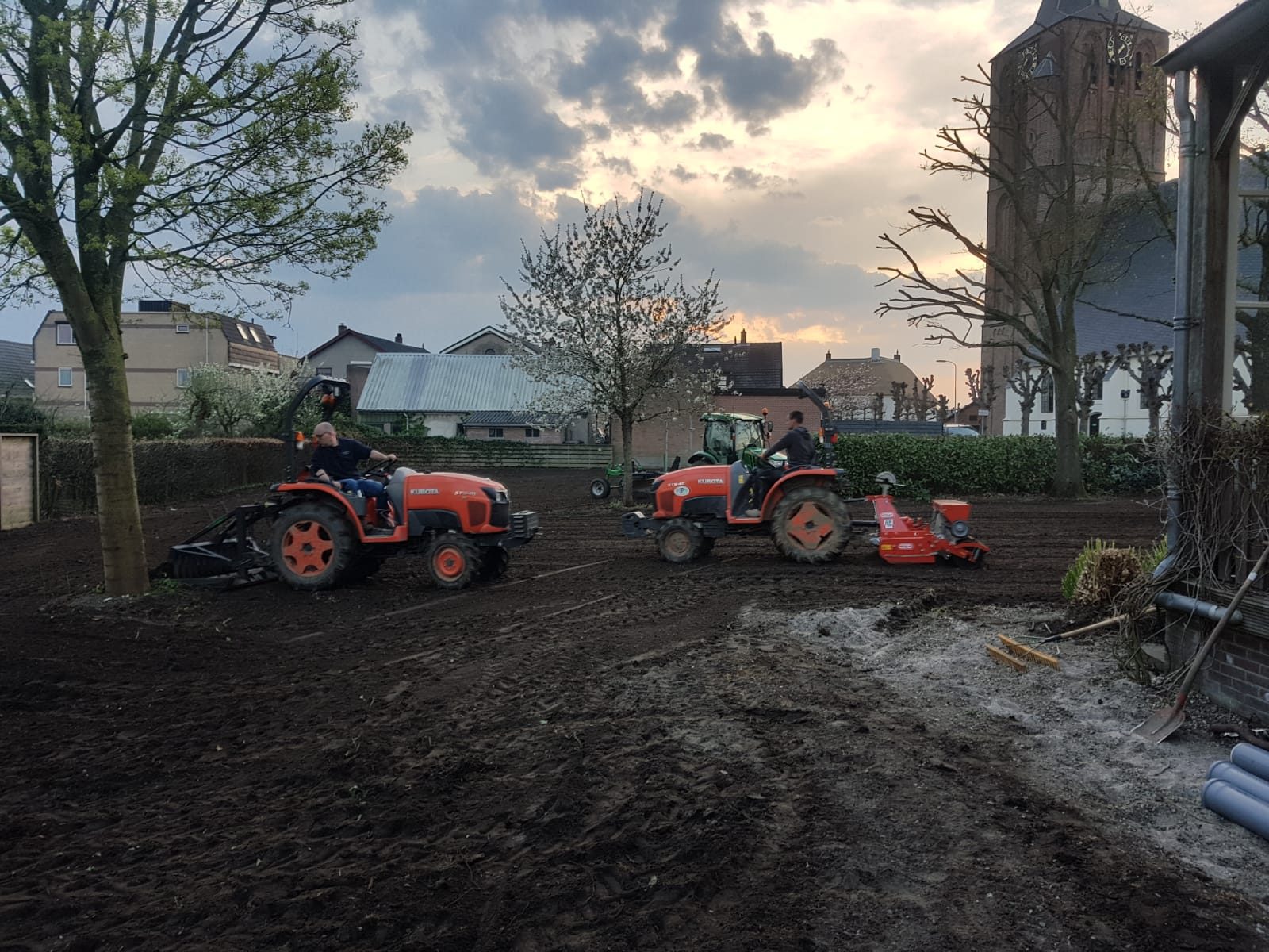 Twee compacte trekkers bewerken en egaliseren de grond van een terrein