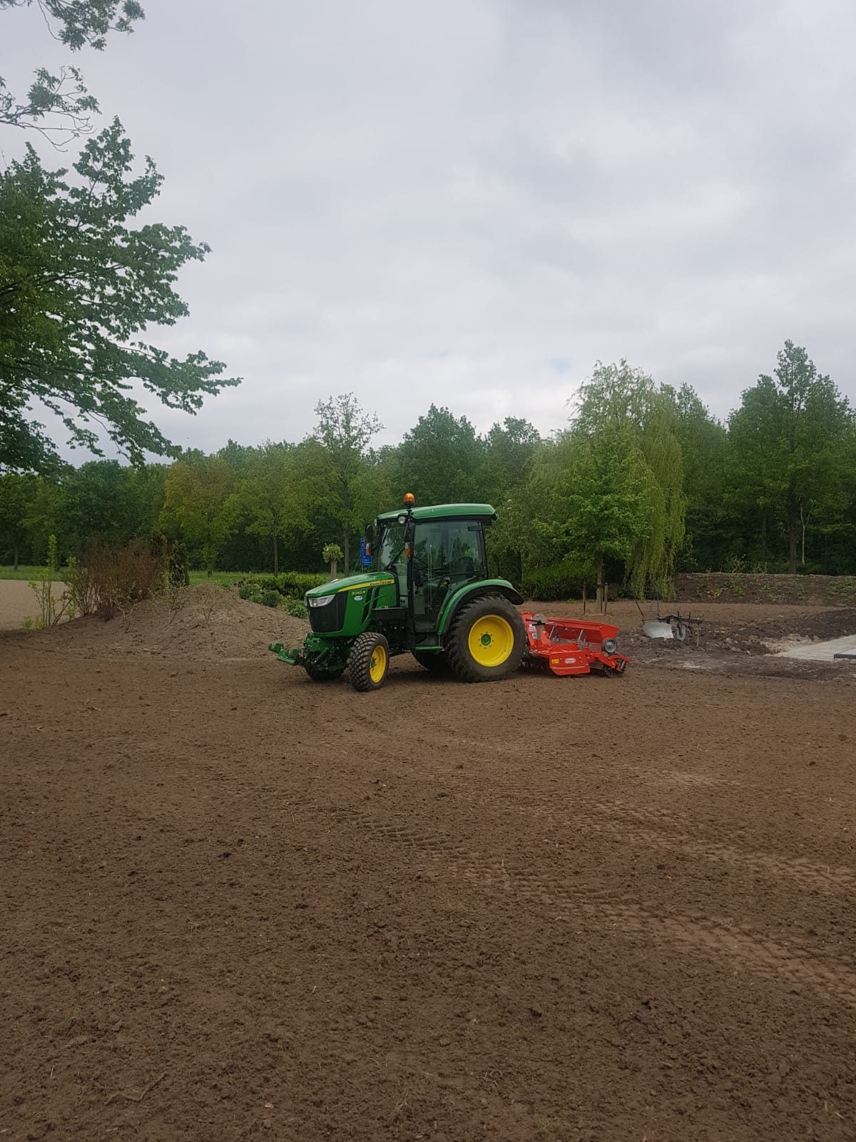 Een trekker met een rotorkopeg bewerkt een kaal terrein